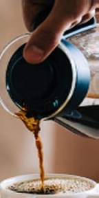 Hand pouring coffee from pot to cup